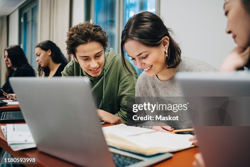 Smiling teenage students studying at desk in school Smiling teenage students studying at desk in school