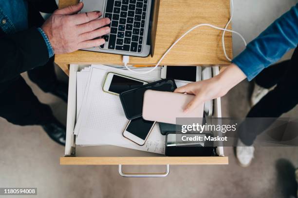 high angle view of female student collecting phone in drawer during exam in school - smart phone angle stock pictures, royalty-free photos & images