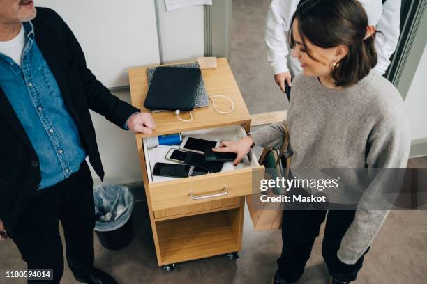 high angle view of teacher standing by student collecting smart phone in drawer at classroom during examination - drawer bildbanksfoton och bilder