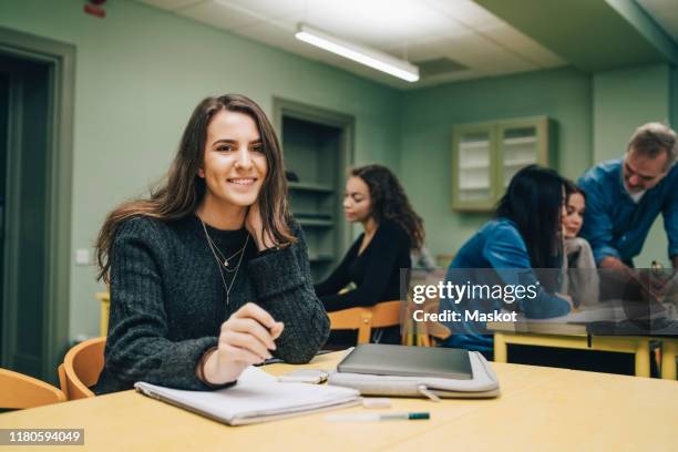 portrait of smiling female student at desk in classroom - five people icon stock pictures, royalty-free photos & images