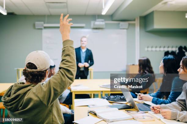 teenage boy with hand raised during lesson in classroom - sweden school stock pictures, royalty-free photos & images