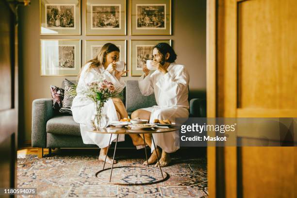 couple in bathrobes drinking coffee while enjoying breakfast at hotel - hotel de lujo fotografías e imágenes de stock