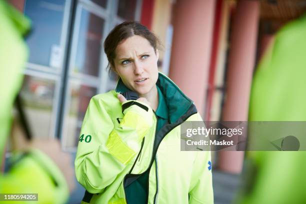 female paramedic looking away while talking on walkie-talkie outside hospital - walkie talkie stock pictures, royalty-free photos & images