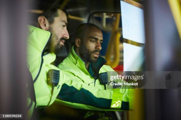 male paramedics discussing while sitting in ambulance at parking lot - rescue worker bildbanksfoton och bilder