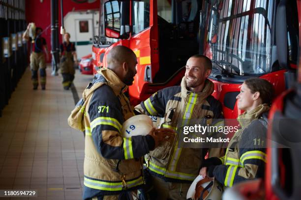 firefighters in uniform talking while standing at fire station - brandslang bildbanksfoton och bilder