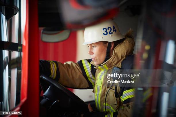 female firefighter wearing helmet sitting in fire truck at fire station - emergency first response stock pictures, royalty-free photos & images