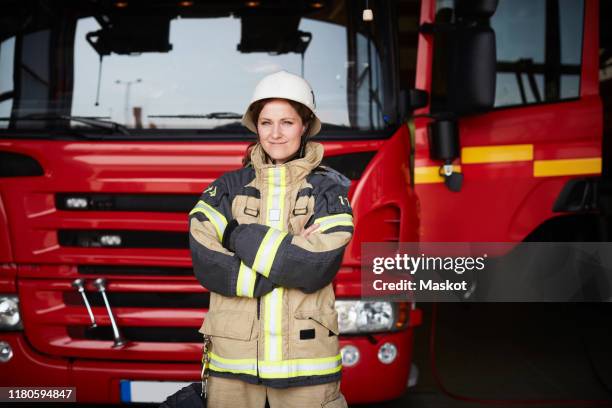 portrait of confident female firefighter standing with arms crossed against fire engine at fire station - fire station - fotografias e filmes do acervo