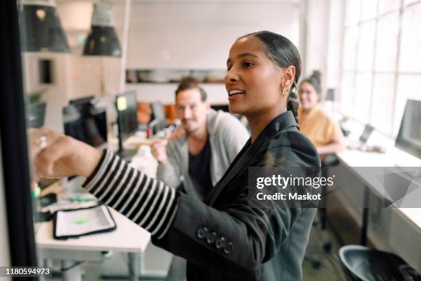 young businesswoman addressing colleagues at office meeting - presentation materials stock pictures, royalty-free photos & images
