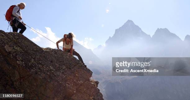 mother belays daughter while climbing rock ridge, using rope - belaying stock pictures, royalty-free photos & images