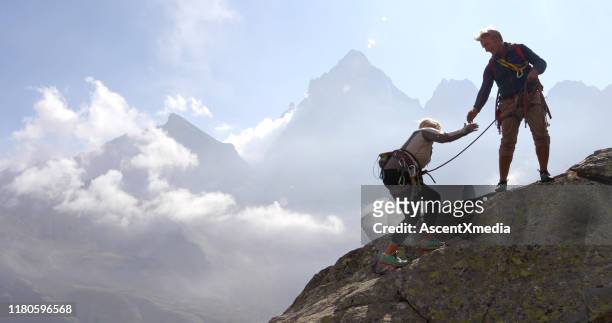 volwassen paar klim rock ridge, met behulp van touw - team climbing up to mountain top stockfoto's en -beelden