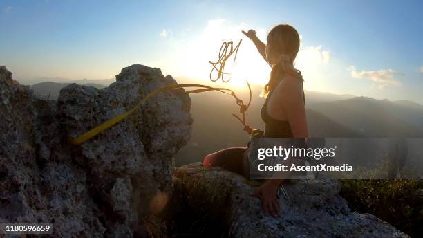 young woman prepares to descend, throws rope from summit - risk imagens e fotografias de stock