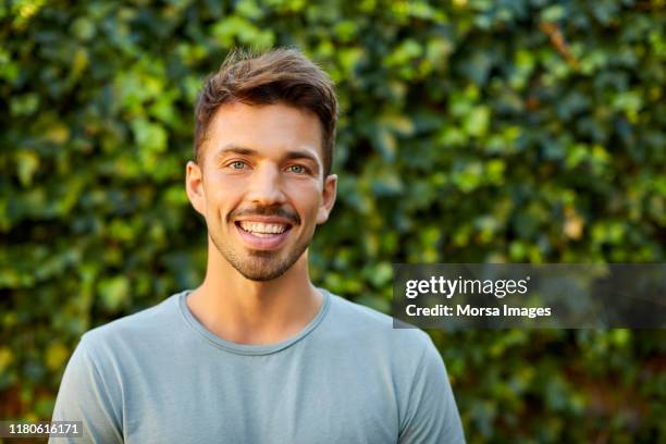 portret van lachende man in blauw t-shirt in de achtertuin - jonge mannen stockfoto's en -beelden