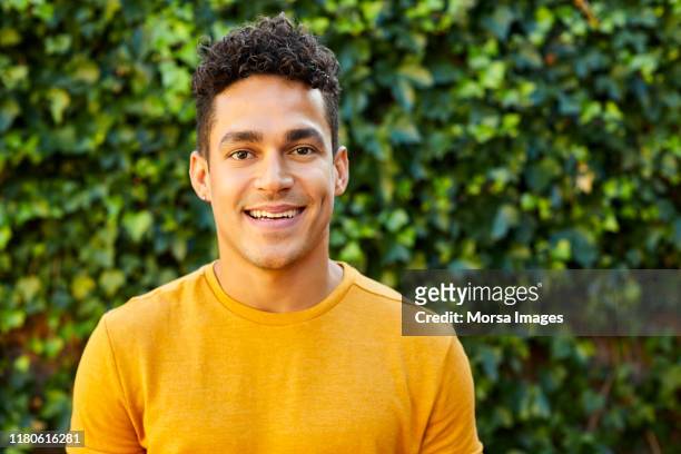 portrait of young man in yellow t-shirt at backyard - shirt stock pictures, royalty-free photos & images