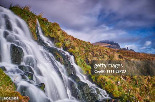 flowing bride's veil waterfall to loch leathan at the storr with old man of storr peak in clouds. - portree imagens e fotografias de stock