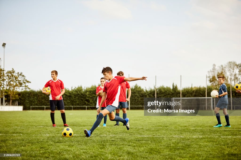 Boy kicking soccer ball on ground during training