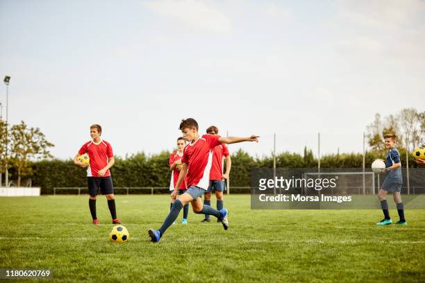 boy kicking soccer ball on ground during training - soccer team stock pictures, royalty-free photos & images