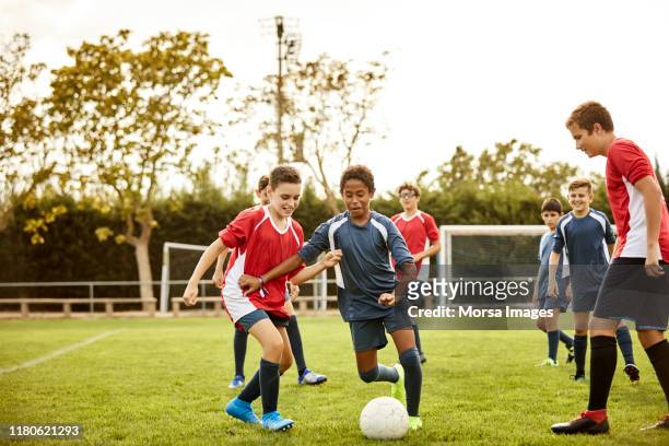 jongens spelen voetbalwedstrijd op oefenterrein - team player stockfoto's en -beelden