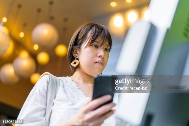 young woman using digital device at counter - merchandise booth stock pictures, royalty-free photos & images