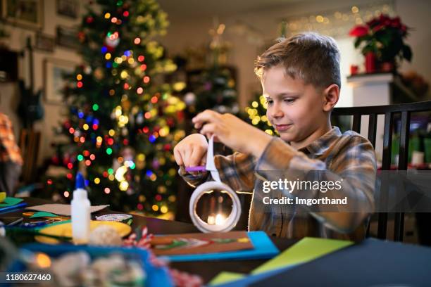 kleiner junge basteln weihnachtskarte - child cutting card stock-fotos und bilder