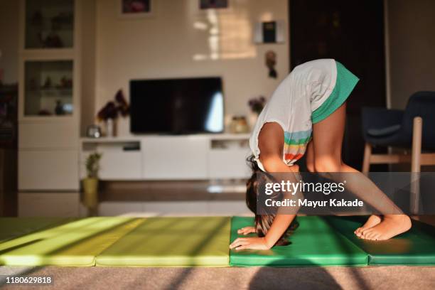 girl practising somersault at home - children yoga stock-fotos und bilder
