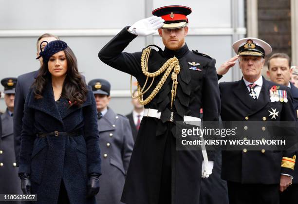 Britain's Prince Harry, Duke of Sussex and his wife Meghan, Duchess of Sussex pay their respects after laying a Cross of Remembrance in front of...