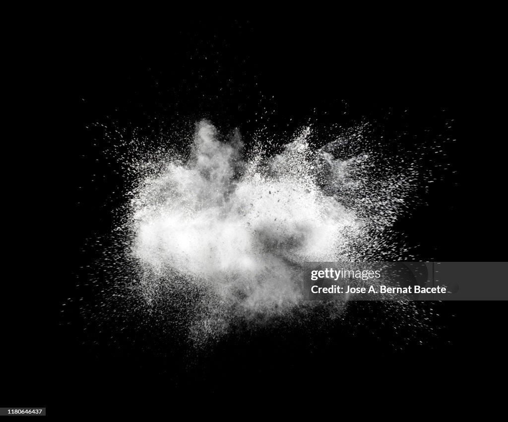 Explosion by an impact of a cloud of particles of powder of white color on a black background.