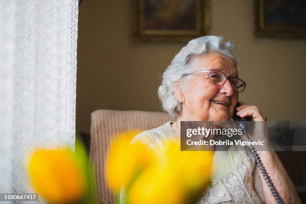 retrato de una mujer mayor hablando con el teléfono - old phone fotografías e imágenes de stock