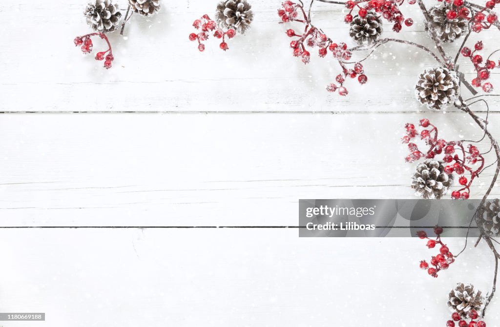 Christmas berry garland border on an old white wood background