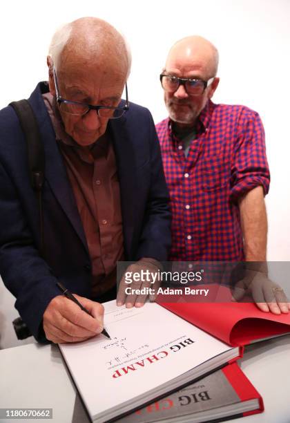 Michael Stipe, former singer of the band R.E.M. , looks on as German photographer Thomas Höpker signs for Stipe a copy of his own book of photos of...