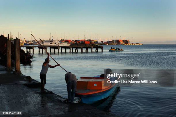 Man arrives at the Honiara Central Markets by boat as performers from the 'Solomon Islands Cultural Group' prepare to leave the island nation to...