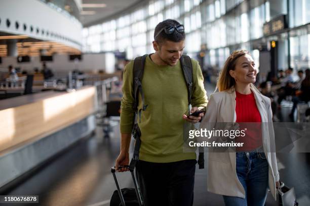 young couple arriving at the airport - suitcase couple stock pictures, royalty-free photos & images