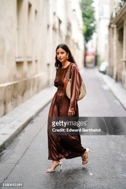 Bettina Looney wears a brown lustrous shiny dress, a Loewe large bag, heels shoes, earrings, outside Thom Browne, during Paris Fashion Week -...