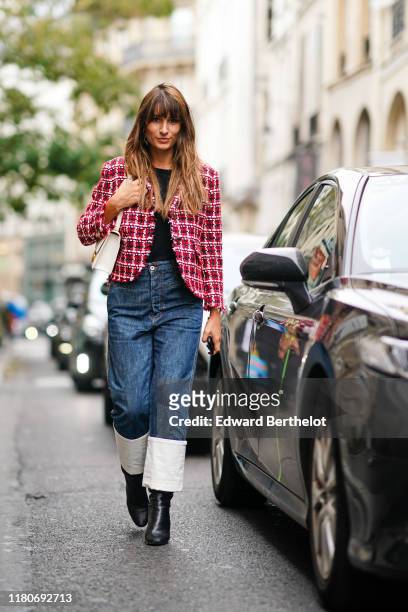 Carlotta Rubaltelli wears a white and red checked tweed jacket, a white bag, a black top, blue denim pants with rolled up hems, black leather shoes,...