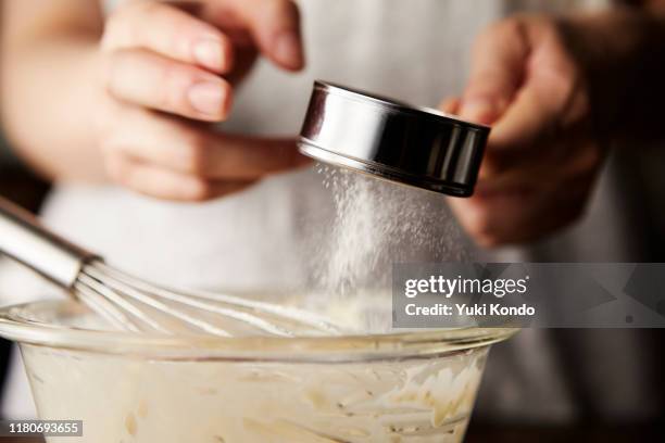 hands sprinkling powder in the bowl. - backpulver stock-fotos und bilder