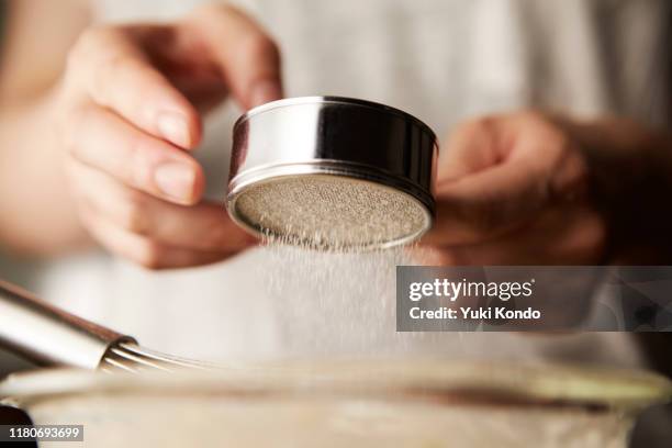 hands sprinkling powder in the bowl. - woman cooking dessert bildbanksfoton och bilder