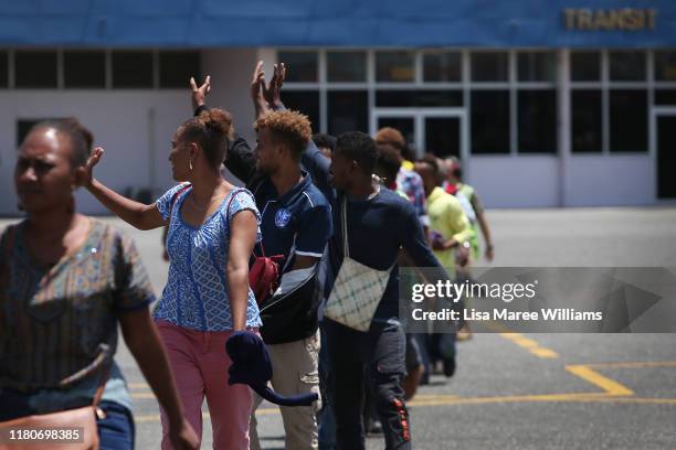 Members of the 'Solomon Islands Cultural Group' wave to friends and family prior to boarding a RAAF Hercules C-130J bound for the Royal Edinburgh...