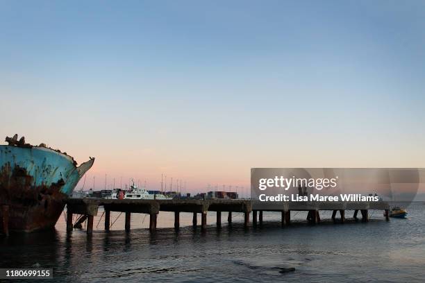 Men walk along a pier at the edge of Honiara Central Markets as performers from the 'Solomon Islands Cultural Group' prepare for the Royal Edinburgh...