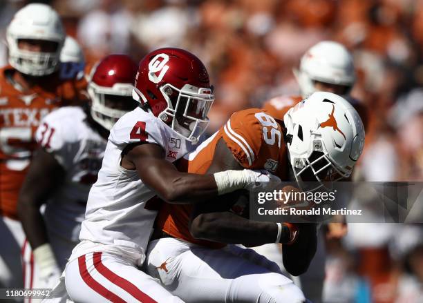 Malcolm Epps of the Texas Longhorns is tackled by Jaden Davis of the Oklahoma Sooners during the 2019 AT&T Red River Showdown at Cotton Bowl on...