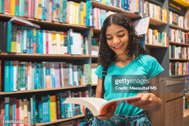 adolescente ragazza che legge libro in biblioteca - educazione secondaria di scuola media foto e immagini stock