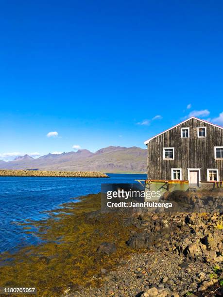 höfn, iceland: rustic wood building near sunlit harbor at midday - anticuado stock pictures, royalty-free photos & images