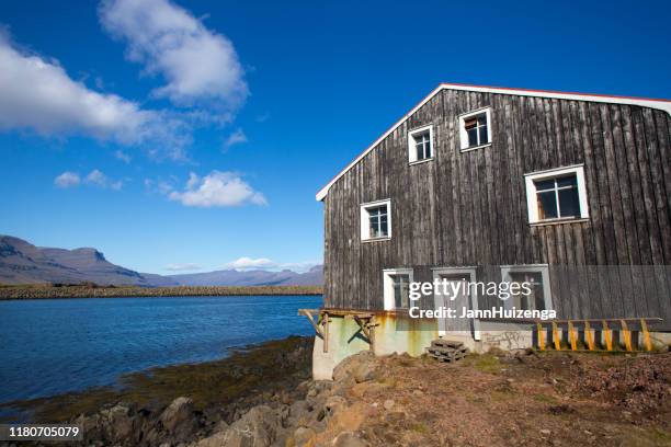 höfn, iceland: rustic wood building near sunlit harbor at midday - anticuado stock pictures, royalty-free photos & images