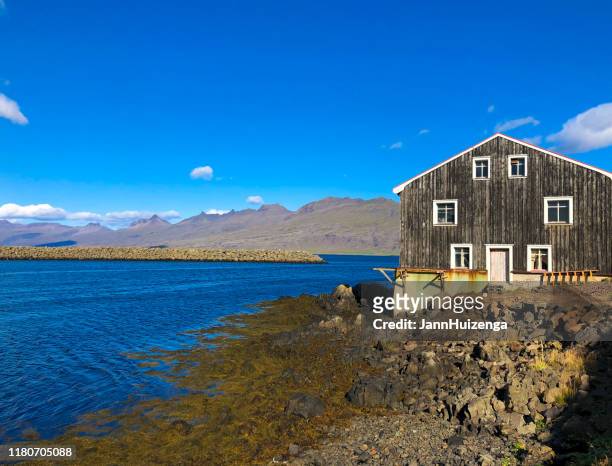 höfn, islândia: edifício de madeira rústico perto do porto de sunlit no meio-dia - anticuado - fotografias e filmes do acervo