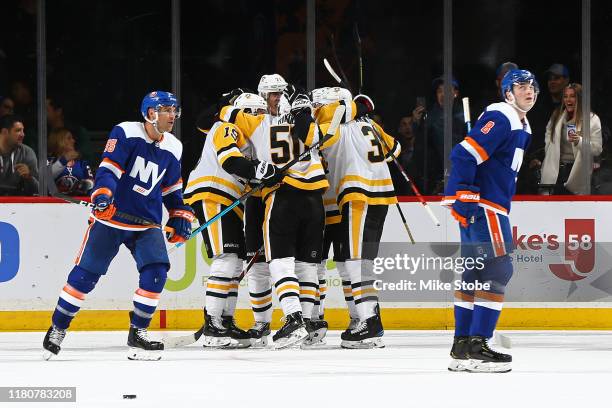 Evgeni Malkin of the Pittsburgh Penguins is congratulated by his teammates after scoring a goal as Cal Clutterbuck and Noah Dobson of the New York...
