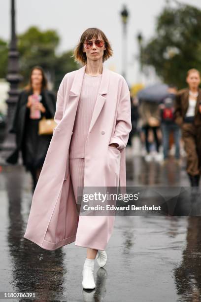 Anya Ziourova wears sunglasses, a pink long coat, a pink top, a pink skirt, white shoes, outside Chanel, during Paris Fashion Week - Womenswear...