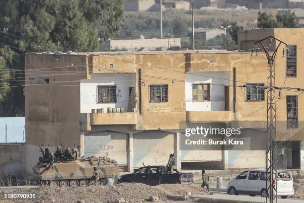 Members of Turkish-backed Free Syrian Army, a militant group active in parts of northwest Syria advance in Syrian city of Tel Abyad, as seen from the...