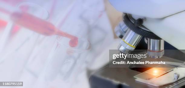 laboratory concept: close up picture of microscope with blurred picture of scientist researcher is transfer chemical reagent by dropper in chemical laboratory. - genetische screening stockfoto's en -beelden