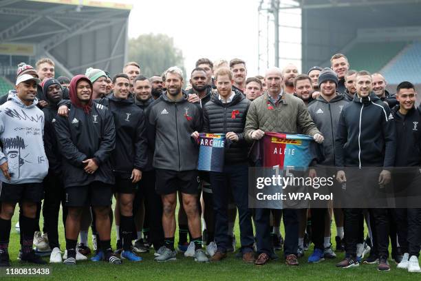 Prince Harry, Duke of Sussex and former rugby player Gareth Thomas pose with gift shirts next to Harlequin rugby club members and their captain Chris...