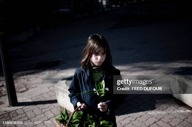 Une petite fille vend le traditionnel muguet « porte-bonheur », le 01 mai 2008 dans les rues de Lyon. Originaire du Japon, la plante aux fières...