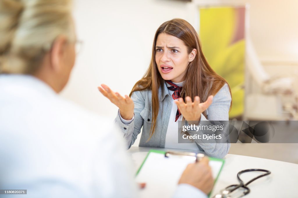 Joven frustrada hablando con su médico.