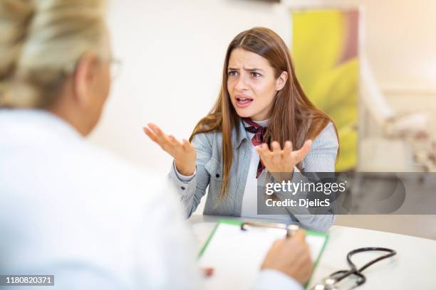 frustrated young woman talking with her doctor. - anger stock pictures, royalty-free photos & images